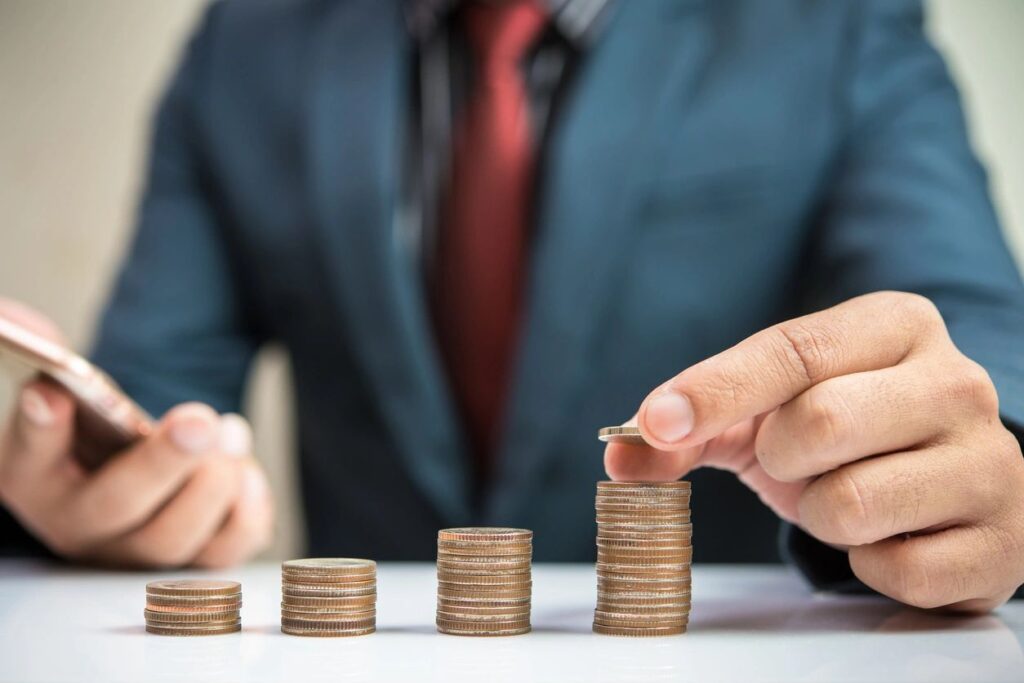 image showing man in suit stacking coins in ascending piles